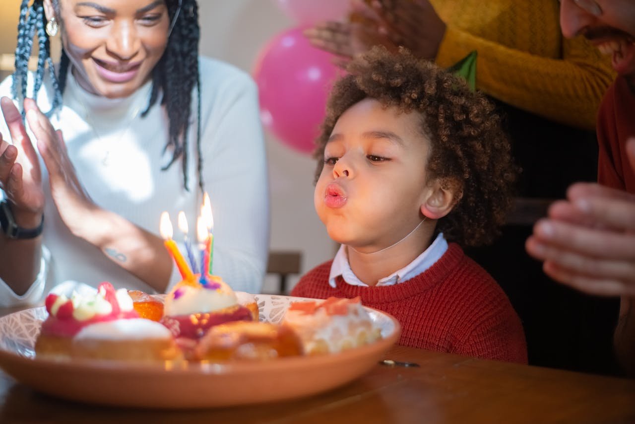 hero-img-02 A joyful birthday celebration with a child blowing out candles surrounded by family, capturing a happy moment.